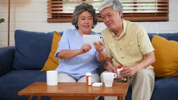 Asian senior couple having medical consultation video chat on mobile.