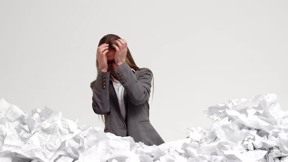 Female office worker stands waist-deep in pile of crumpled papers