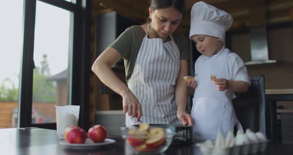 Mom and Son in a Chef's Uniform Knead the Dough for Apple Pie