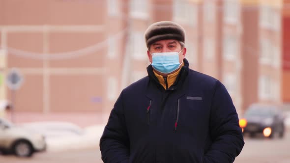 Closeup of a Man in a Medical Mask Stands and Looks Forward and Around