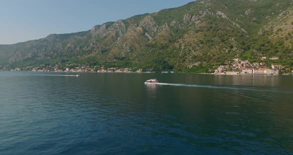 speeding ship with tourists in kotor bay with mountains on background
