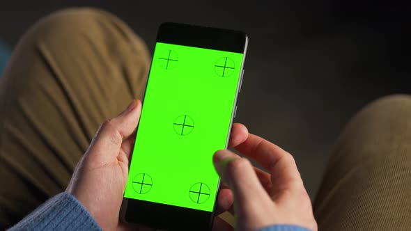 Man Using Smartphone with Green Mockup Screen in Vertical Mode