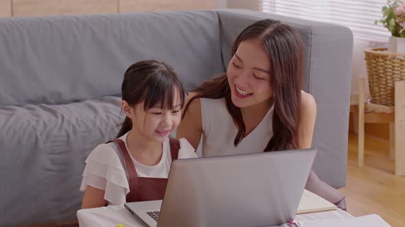 Asian young mother and her daughter have video call conference with family having fun together