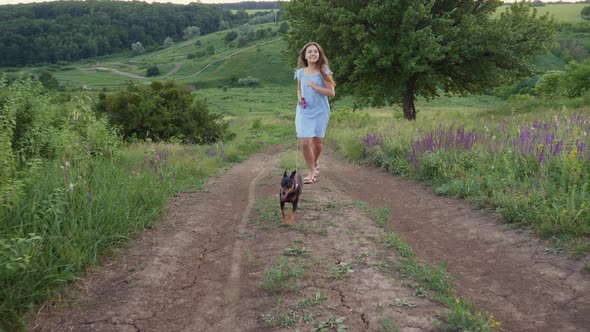 Smiling Teenage Girl Walking Her Dog on a Leash in Nature