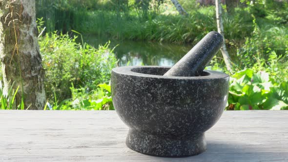 Hand is Putting Fresh Spices Into the Grey Stone Mortar in Slow Motion Outdoors