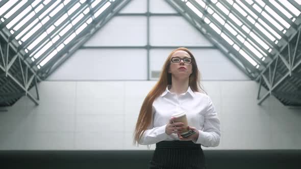 Successful young business woman with cup of coffee walks  business center.