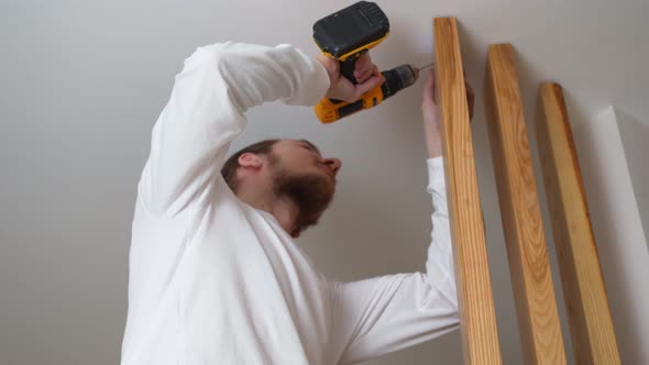 the Carpenter Screws with a Screwdriver Wooden Ash Lamellae to the Ceiling