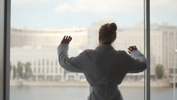 Back View of Woman in Sleepwear Wake Up in Morning Stretching Looking Out Panoramic Window
