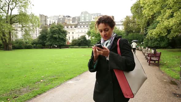 Young woman watching at smart phone looking for directions in London