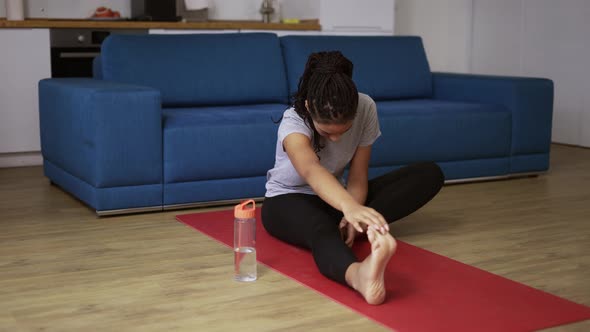 Young African Woman on a Mat in Living Room Hard to Do Sport Exercises Doing Stretching