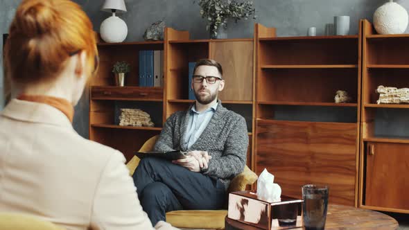 Male Counselor Speaking with Female Patient and Taking Notes