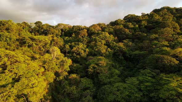 Epic reveal of magnificent mountainous jungle landscape during sunset. Drone flying low and fast ove