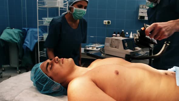 Male surgeon resuscitating an unconscious patient with a defibrillator