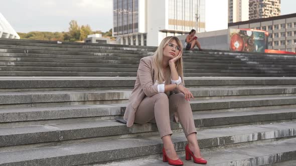 Business woman after work sits on the steps and dreams of the future.