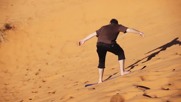 Tourist On Board Surfing Down Sand Dune