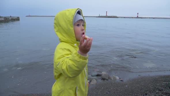Little Boy in Yellow Jumpsuit Plays on Black Sea Coast