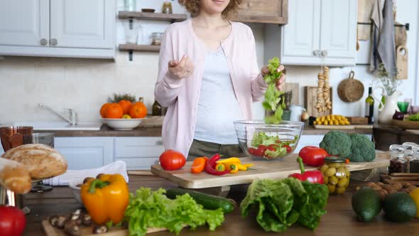 Pregnant Woman Cooking Fresh Salad From Organic Vegetables On Kitchen
