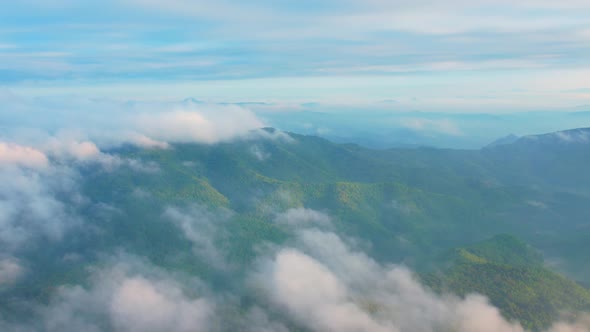 4K Flying through the clouds above mountain tops. Tropical forest with smoke and fog.