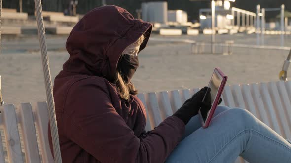 Girl in a Mask Outdoors Uses a Tablet. Insulation