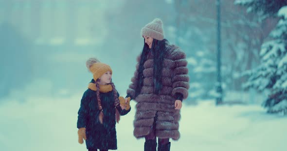 Girl with Her Mother Go Under Heavy Snowfall