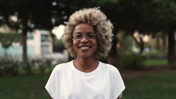 American Hispanic Young Woman with Afro Hair Looking at Camera and Smiling