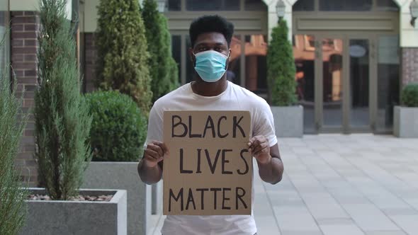 African American Man in a Medical Mask Holding a Poster with the Inscription Black Lives Matter