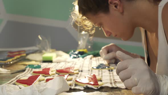 Woman decorates homemade vehicle shaped cookies with sugar icing. Close up push in shot 4K