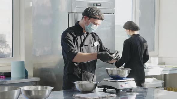 Professional Male Cook in Uniform and Covid Face Mask Beating Eggs in Slow Motion As Woman Working