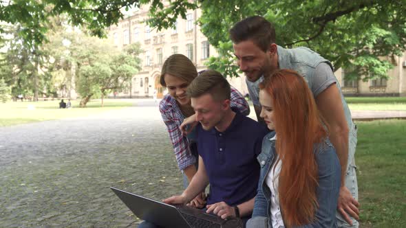 Four Students Laugh at What They See on Laptop on Campus