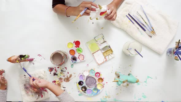 Step by step. Little girls painting paper mache unicorn with acrylic paint.