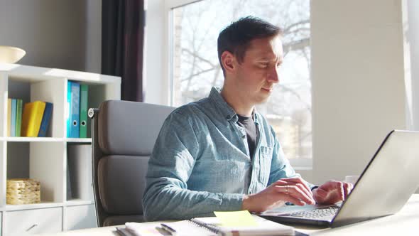 Young male entrepreneur works at home office at the computer.