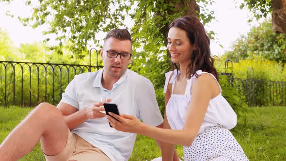 Happy Couple with Smartphone at Picnic in Park