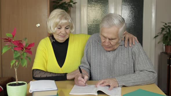 Happy Old Mature Retired Couple Sit on Table at Home Enjoying Free Time Leisure