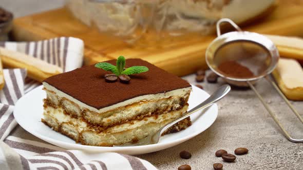 Portion of Traditional Italian Tiramisu dessert on grey concrete background