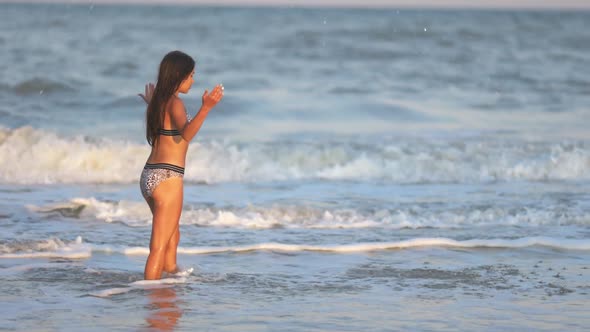 A Girl with Loose Hair Walks on the Sea with Waves and Enjoys the Sun