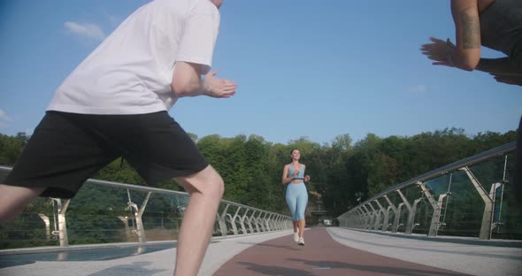 Athletic Woman Runs Towards Other Athletes Along Bridge