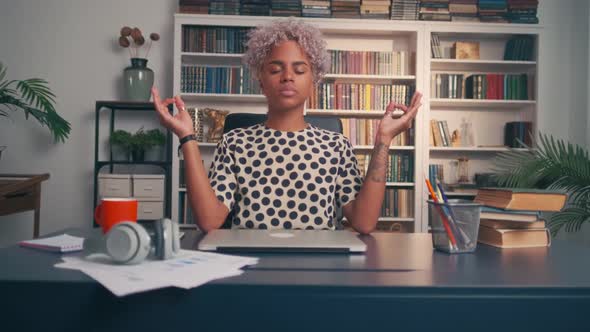 Business Woman Relaxes and Meditates Sitting at Table During Break at Work