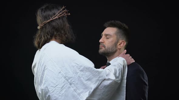 Messiah in Crown of Thorns Hugging Crying Male on Dark Background, Support