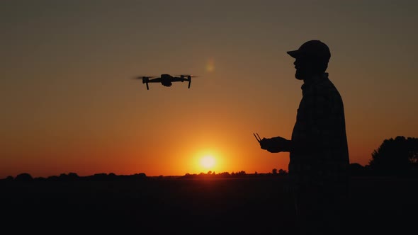 Silhouette of a Man Controlling a Drone at Sunset