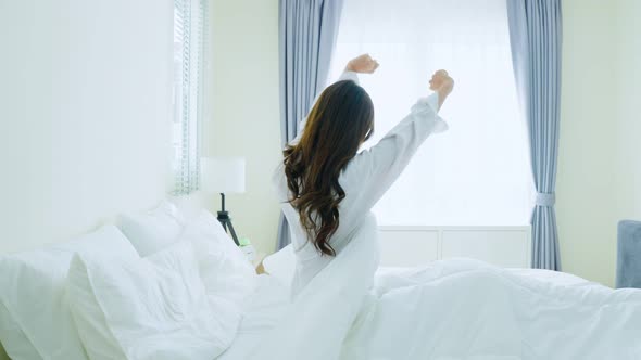 Asian beautiful girl in pajamas wake up in the morning with happiness.