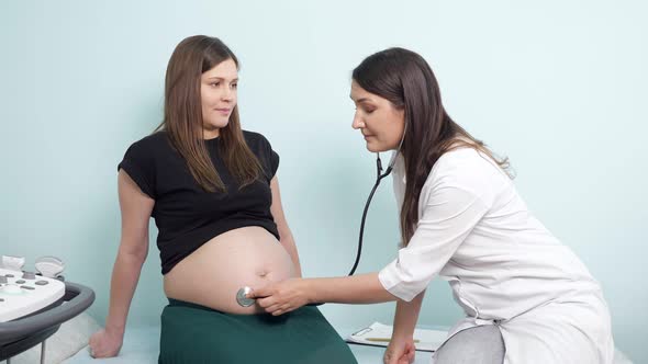 Doctor Examines Pregnant Lady Belly with Stethoscope