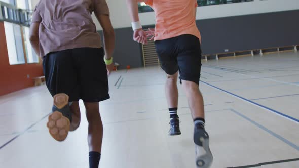 Diverse male basketball team and coach running and wearing sportswear