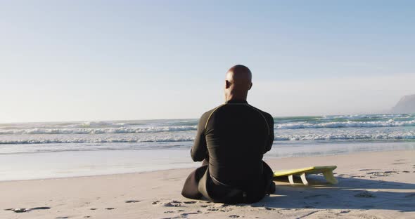 Senior african american man sitting with a surfboard at the beach