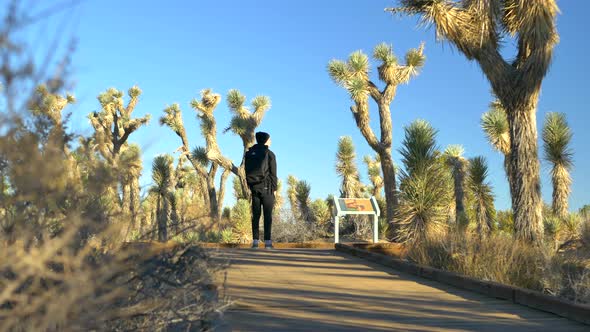 A young man hiker with a backpack and a beanie hiking through a public desert habitat nature preserv