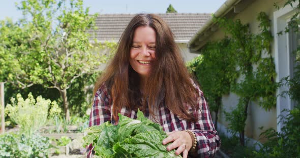 Portrait of happy caucasian woman holding lettuce in garden