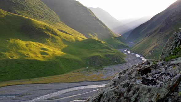 Tusheti, Caucasus, Georgia. Mountains Covered with Green Grass in Sunset Rays. Mountain River