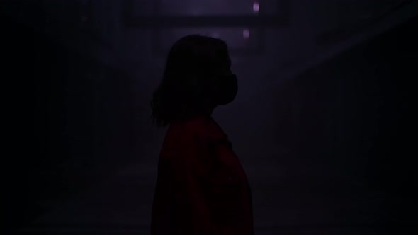 Woman in a Face Mask Standing in a Dark Tunnel with Red Lights