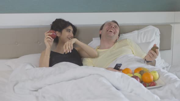 Couple in bedroom. Watching TV.