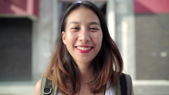 Cheerful young Asian backpacker woman feeling happy smiling to camera while traveling at Chinatown.