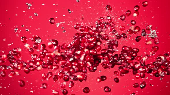 Super Slow Motion Shot of Fresh Pomegranate Seeds and Water Side Collision on Red at 1000Fps